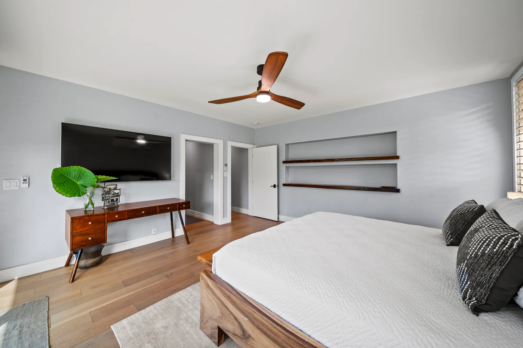 Un dormitorio con una cama grande, un televisor en la pared y estantes de madera.