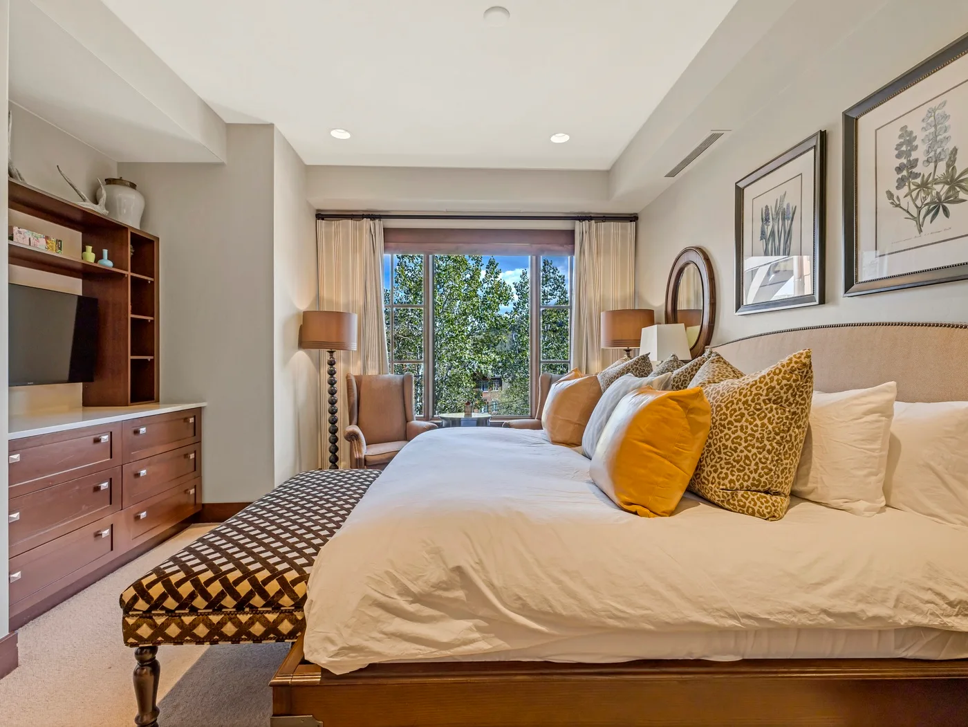 Un dormitorio con una cama grande y una ventana con vista a árboles frondosos.
