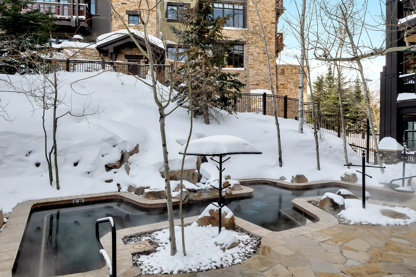 Zona de piscina exterior cubierta de nieve junto a un edificio de piedra.