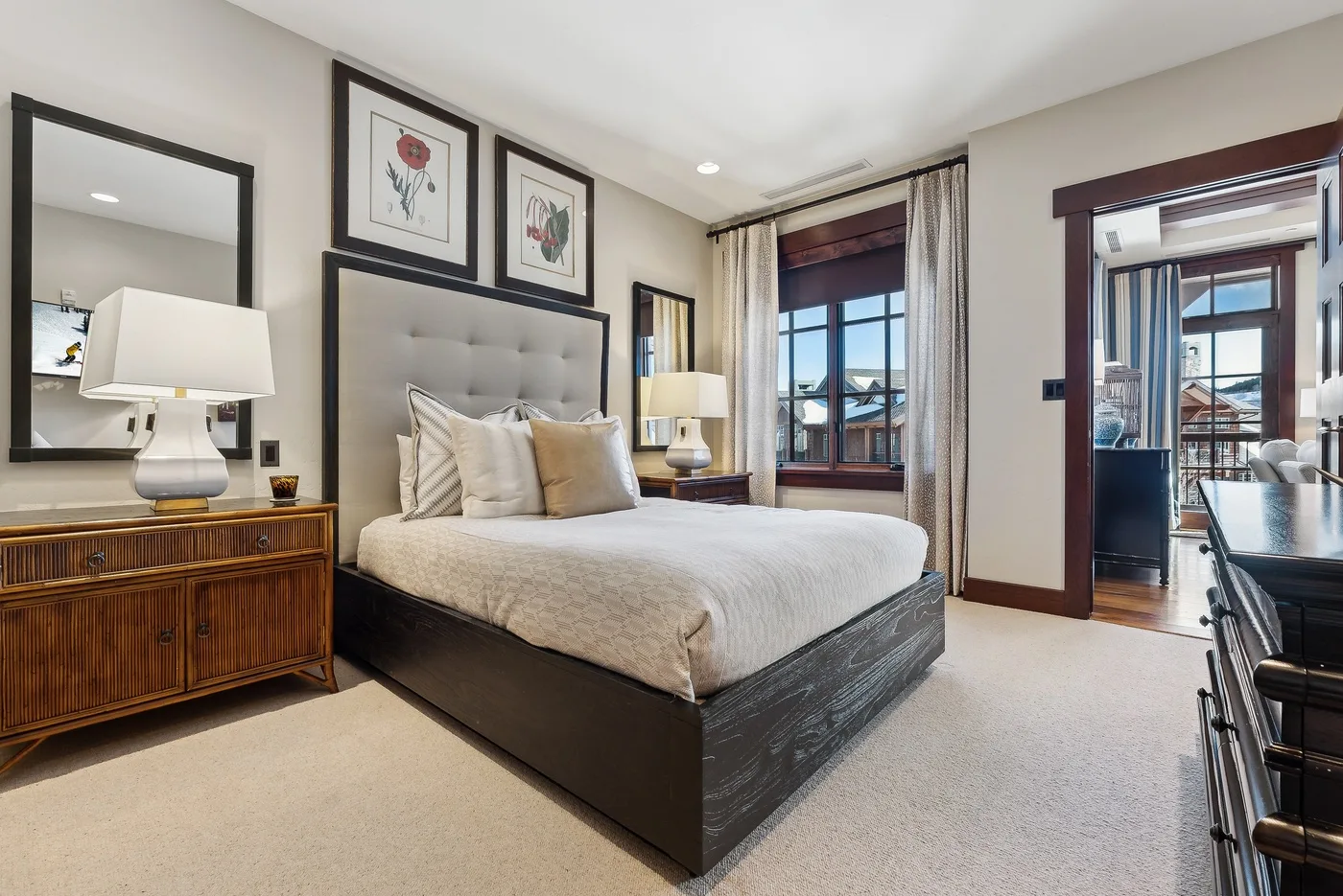 Un dormitorio con una cama, cuadros enmarcados y una ventana con vistas al exterior.