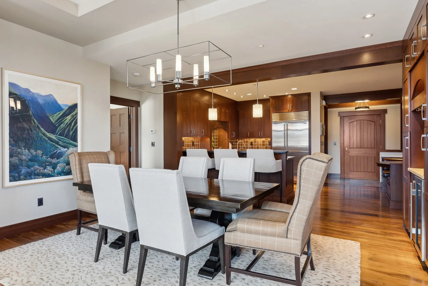 A dining area with upholstered seating, a table, and a hanging light fixture.
