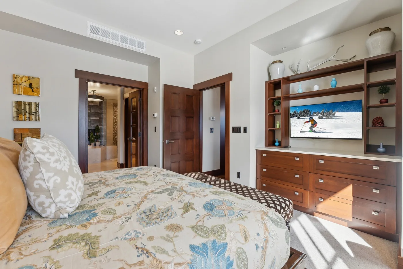 Un dormitorio con una colcha estampada y un mueble empotrado con televisor.