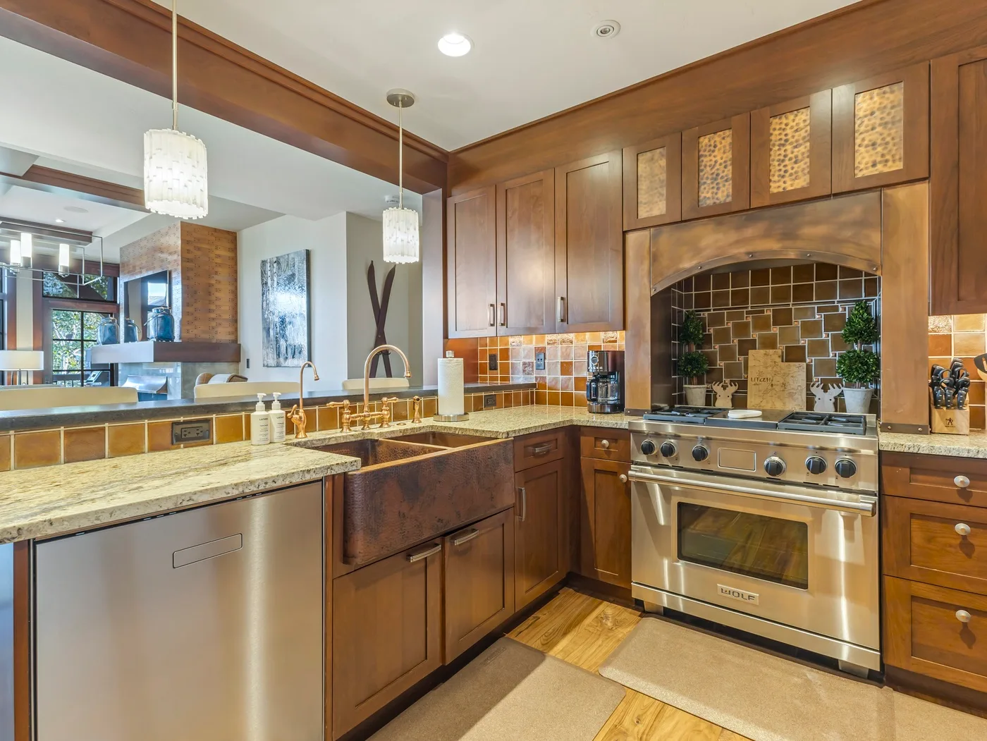 Una cocina con paneles de madera, una estufa de acero inoxidable y encimeras de piedra.