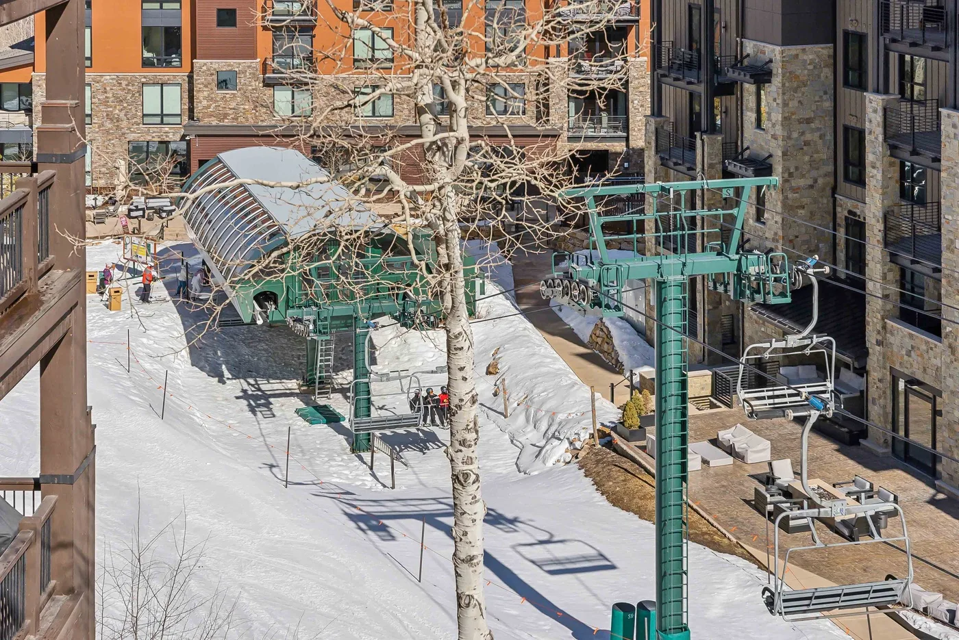 Una zona de esquí cubierta de nieve con estructuras verdes de elevación junto a edificios.