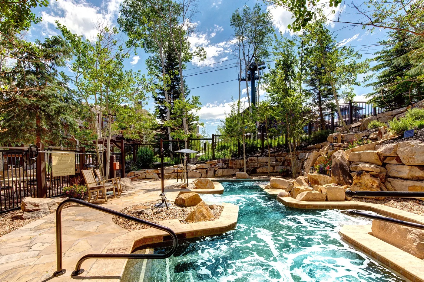 Una piscina exterior rodeada de rocas grandes y árboles.
