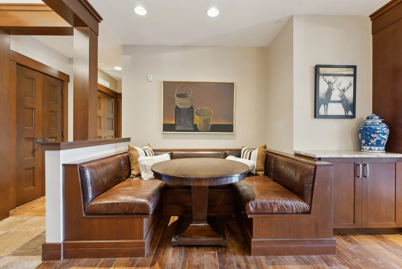 Un rincón de comedor con asientos integrados alrededor de una mesa redonda de madera.