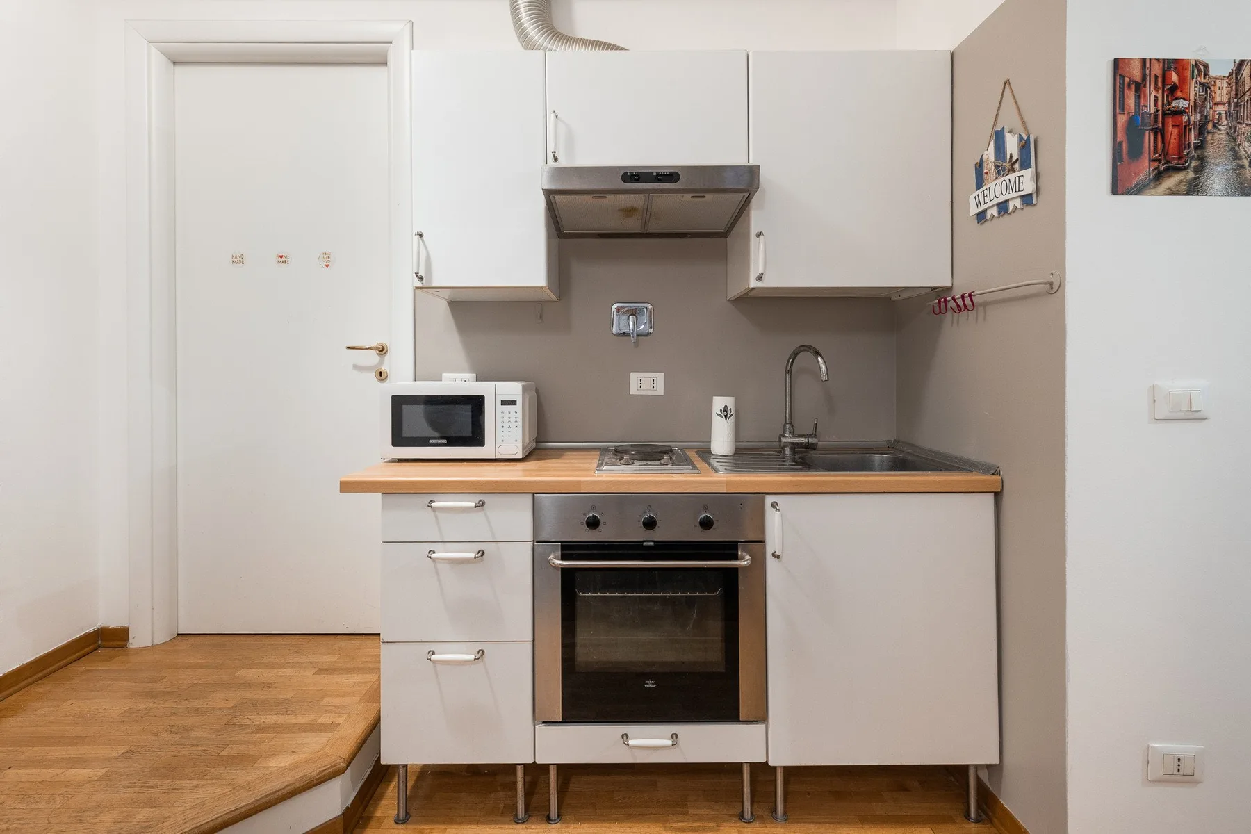 A compact kitchen with white cabinets, a countertop, and a built-in oven.