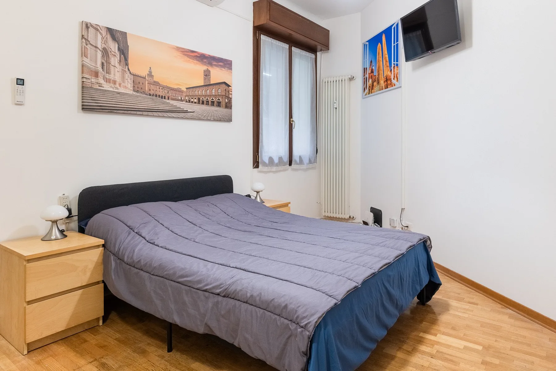 A bedroom with a bed, bedside tables, and a window.