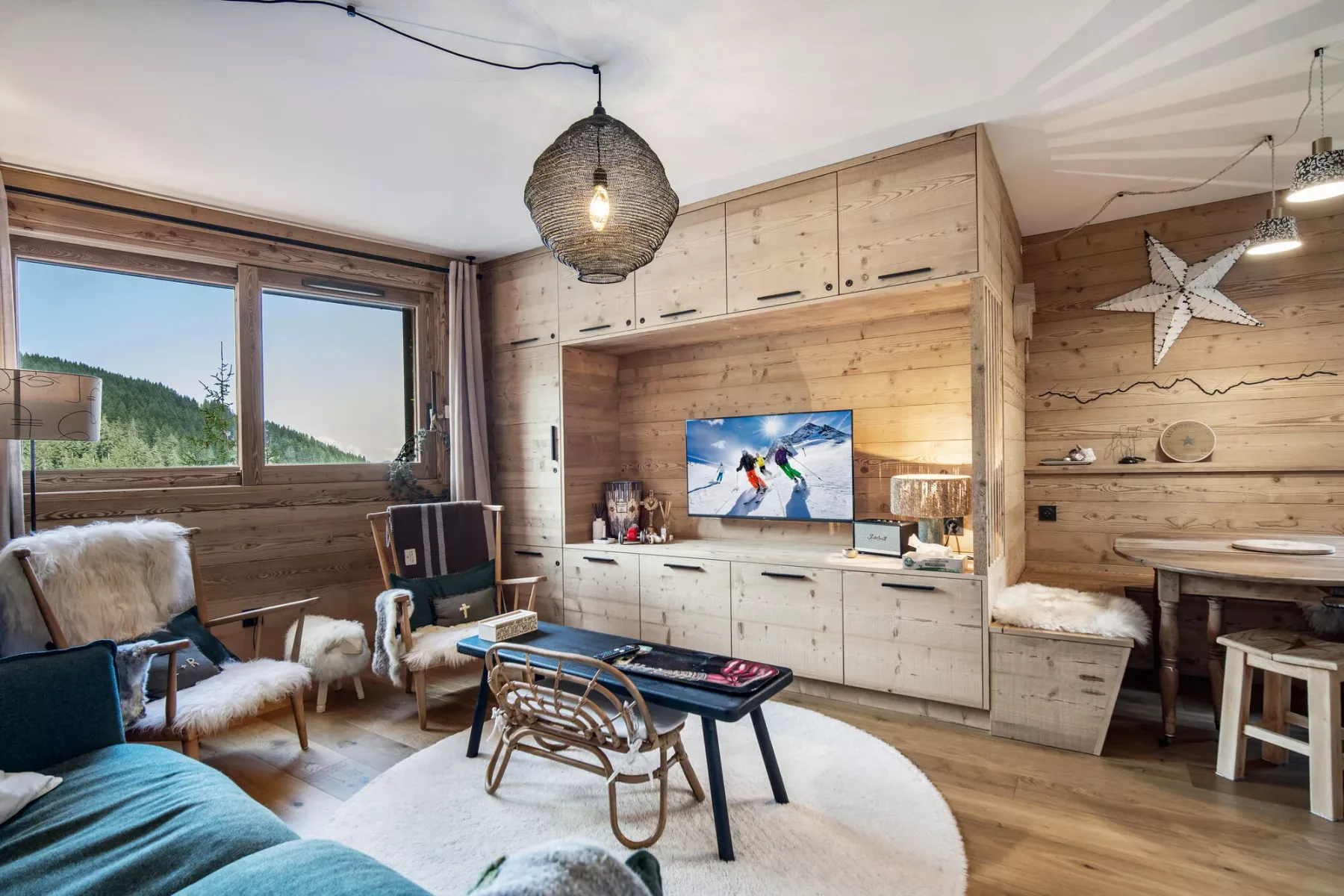 A wood-paneled living room with seating, a television, and large windows.