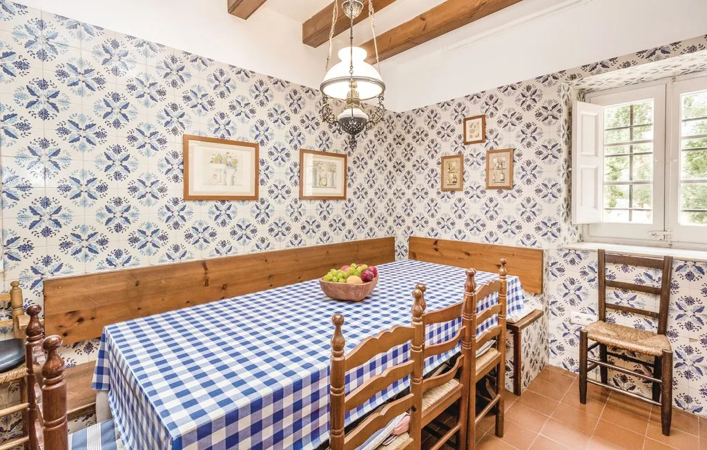 Un comedor con una mesa larga cubierta con un mantel de cuadros azules y blancos.