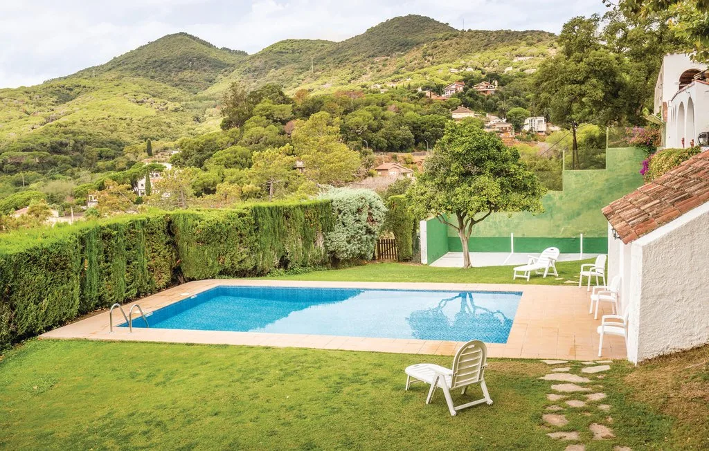 Piscina al aire libre y césped con colinas verdes al fondo.
