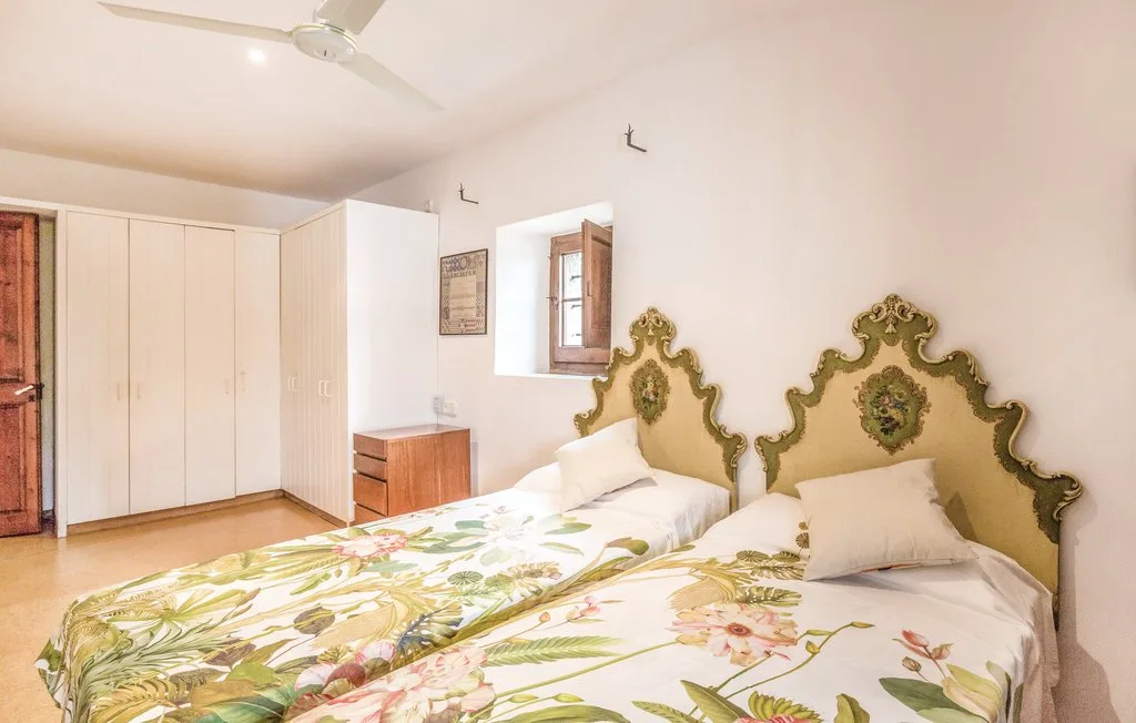 Un dormitorio con dos camas, cabeceros verdes ornamentados y ropa de cama floral.