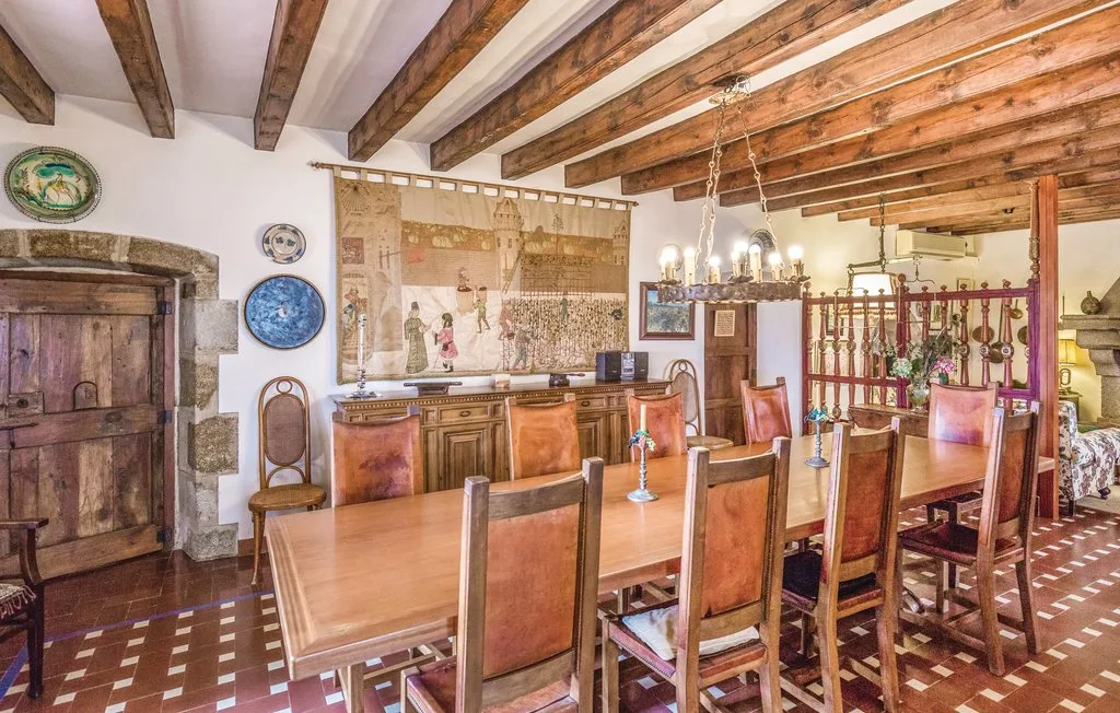 Un comedor rústico con una larga mesa de madera bajo vigas expuestas.