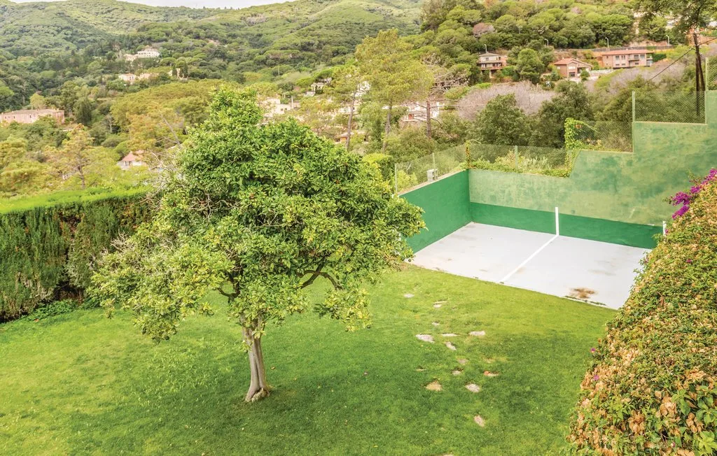 Un jardín con césped, una pequeña pista y vistas a colinas verdes.