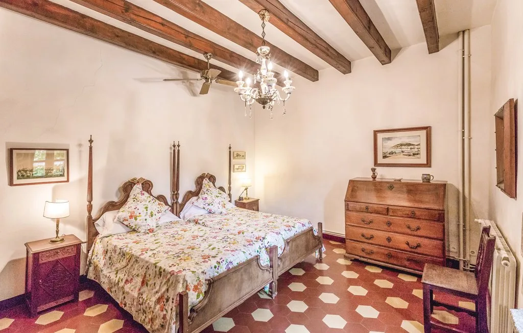 Un dormitorio con dos camas, ropa de cama estampada y vigas expuestas en el techo.