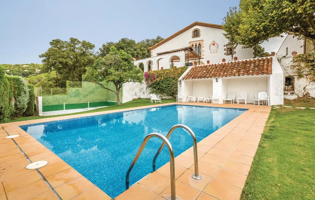 Una piscina al aire libre está junto a un edificio blanco con un patio cubierto.