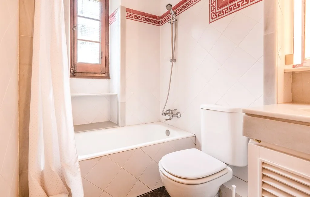 Un baño alicatado con bañera, ducha e inodoro.