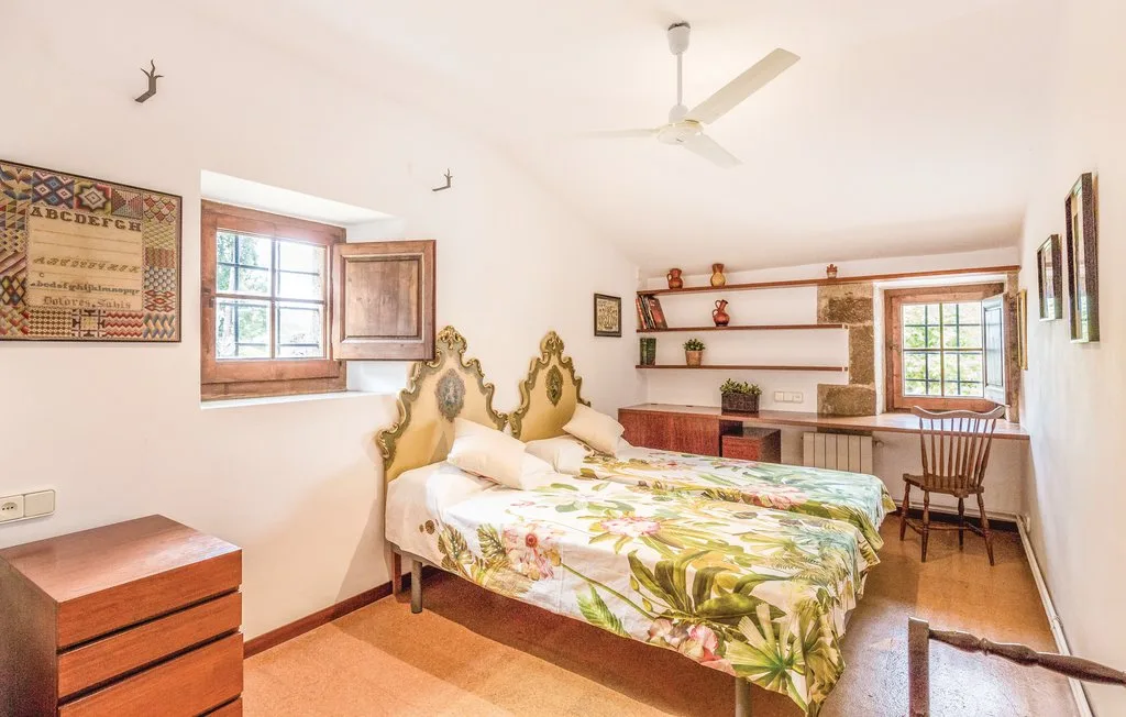 Un dormitorio con una cama doble, ropa de cama floral y contraventanas de madera.