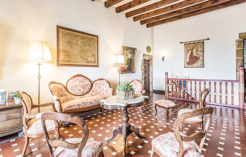 Una sala de estar tradicional con asientos estampados y vigas de madera expuestas en el techo.