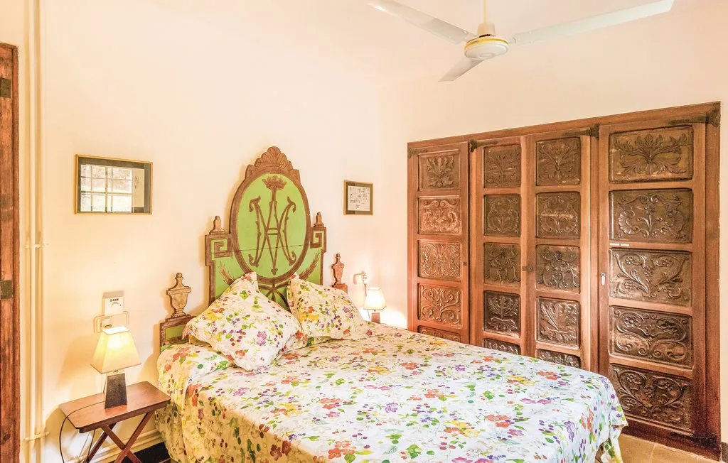 Un dormitorio con una colcha floral y un cabecero de madera ornamentado.