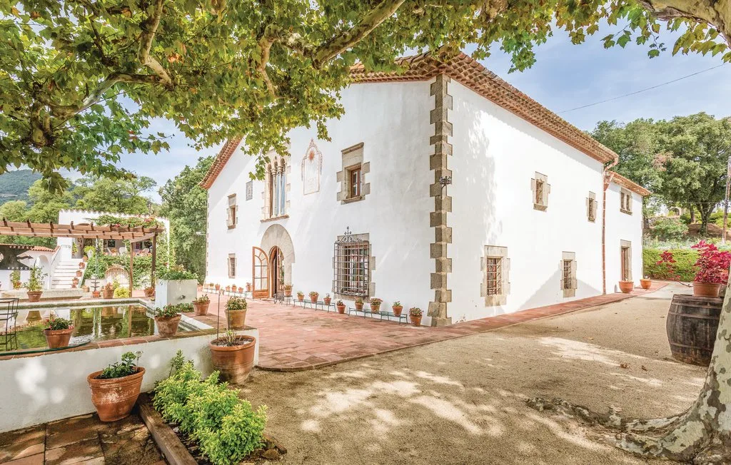 Un edificio blanco de estuco con tejas de terracota se alza junto a un patio pavimentado.