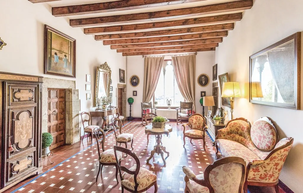 Una sala luminosa con asientos estampados, vigas de madera y ventanas altas.