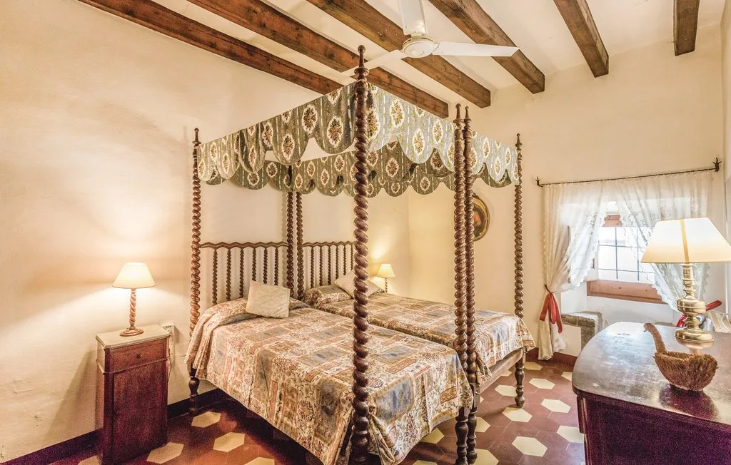 Un dormitorio con una cama con dosel, vigas vistas y una ventana.