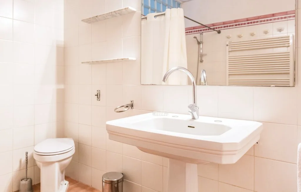 Un baño con azulejos, lavabo suspendido e inodoro.