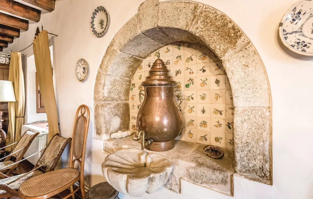Un interior rústico muestra un gran recipiente de cobre en un nicho de piedra con azulejos.