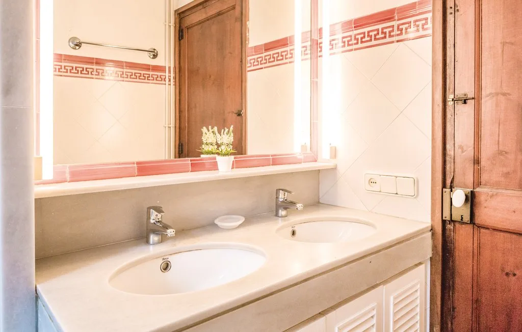 Un tocador de baño con dos lavabos bajo un espejo grande.