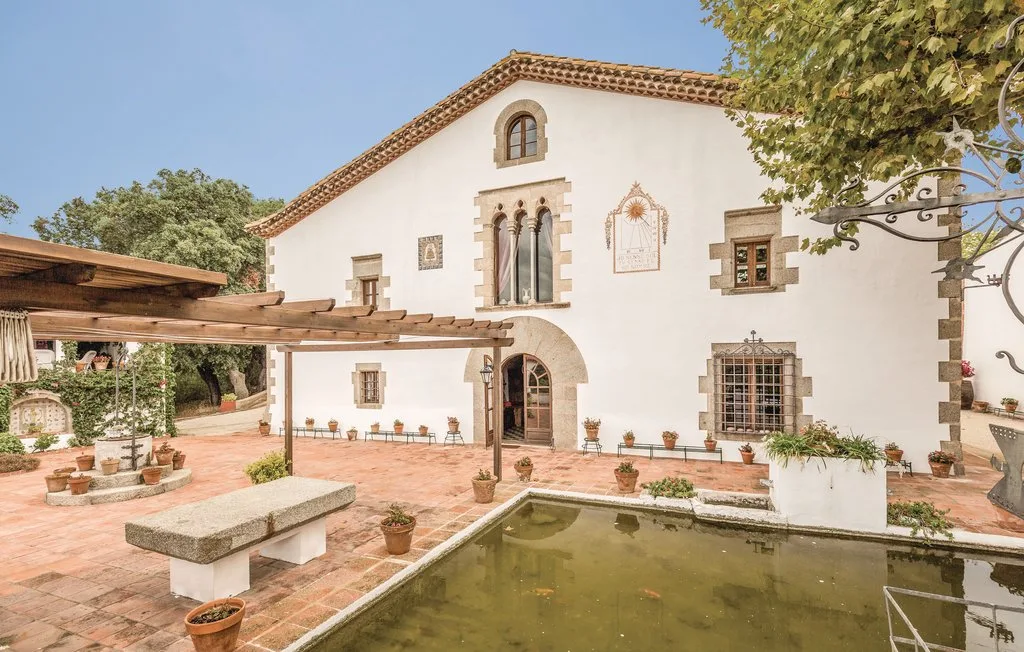 Un edificio blanco de estuco se abre a un patio con un estanque rectangular.