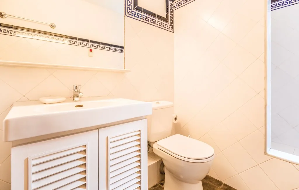 Un baño con azulejos, lavabo y inodoro.