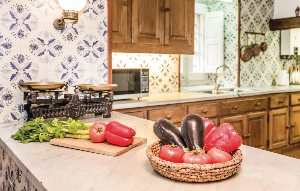 Una cocina con gabinetes de madera, paredes de azulejos y verduras sobre la encimera.