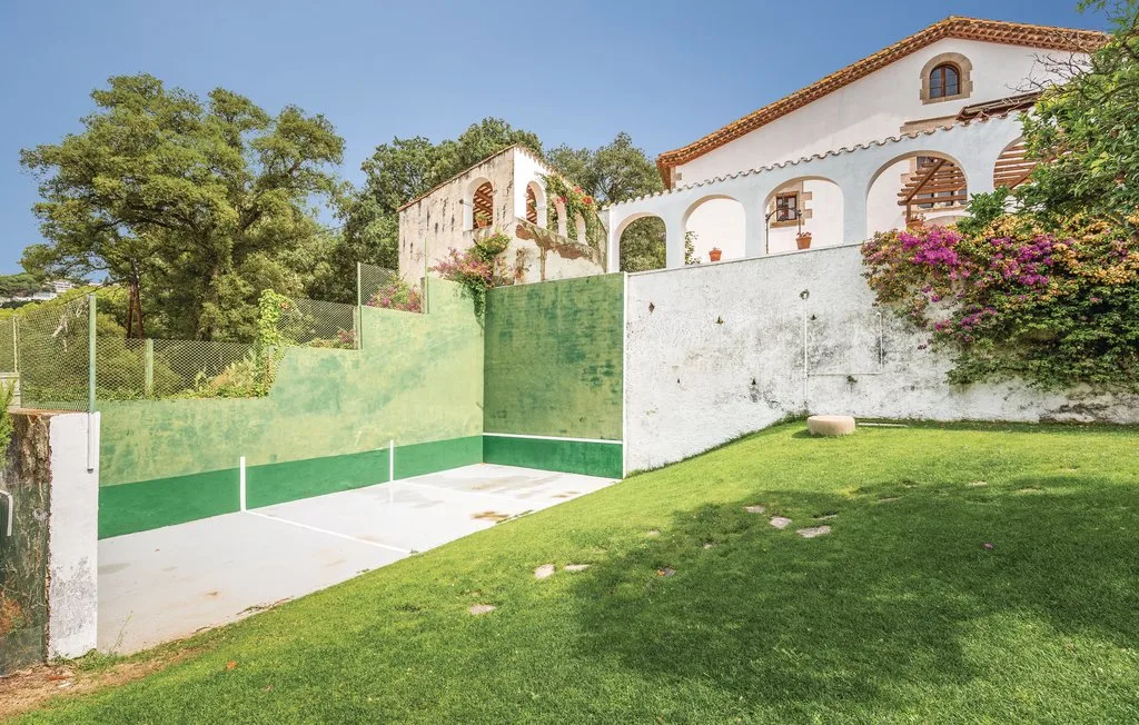 Una cancha deportiva al aire libre está junto a un césped y un edificio blanco.