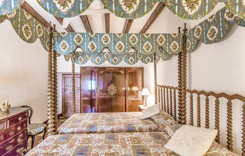 Un dormitorio con camas estampadas y tela decorativa colgada sobre ellas.