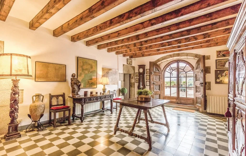Una estancia amueblada con suelo a cuadros, vigas de madera y una puerta acristalada con arco.