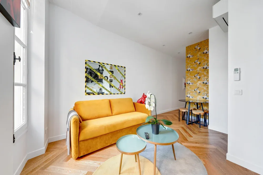 Una sala luminosa con asientos naranjas, una mesa pequeña y arte en la pared.