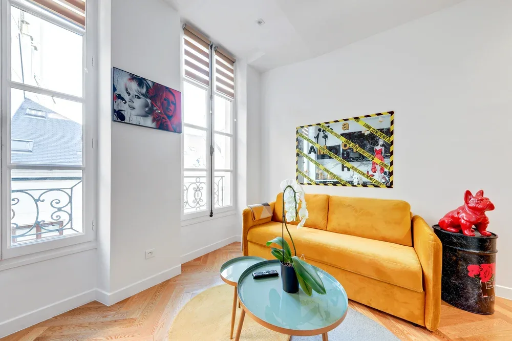 A bright living room with orange seating and a glass coffee table.