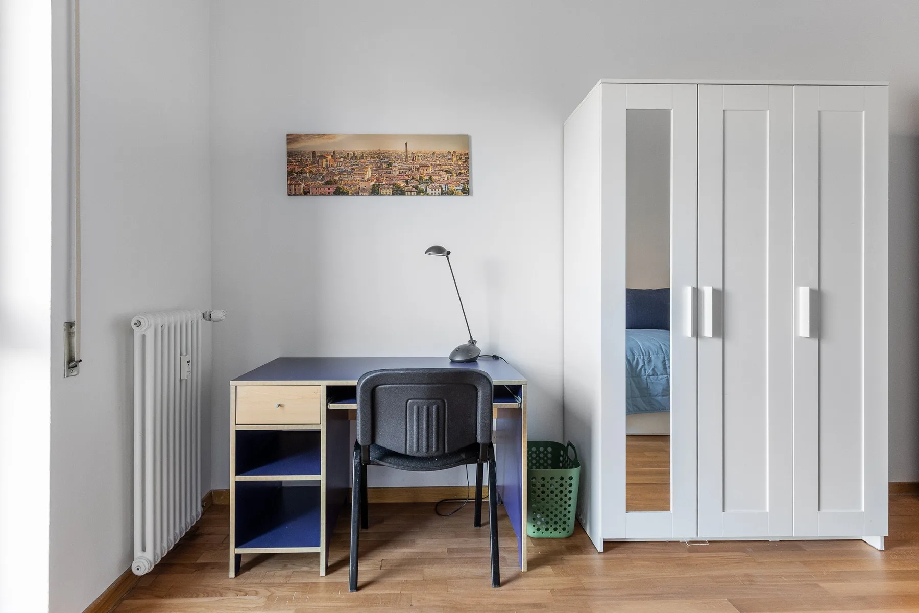 A bright bedroom workspace with a desk, chair, and wardrobe.