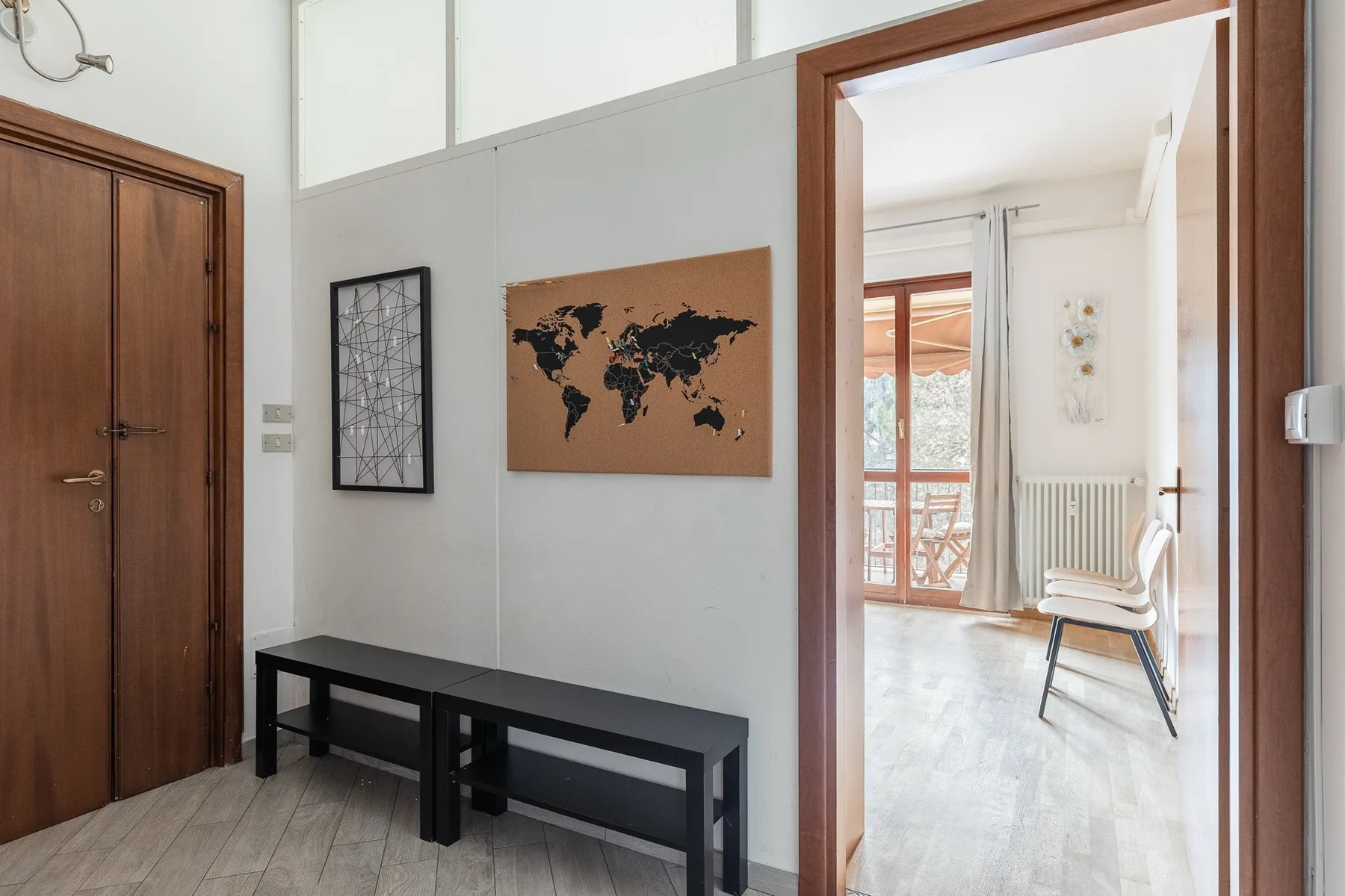 A bright hallway with wall art and an open doorway to a sunlit room.