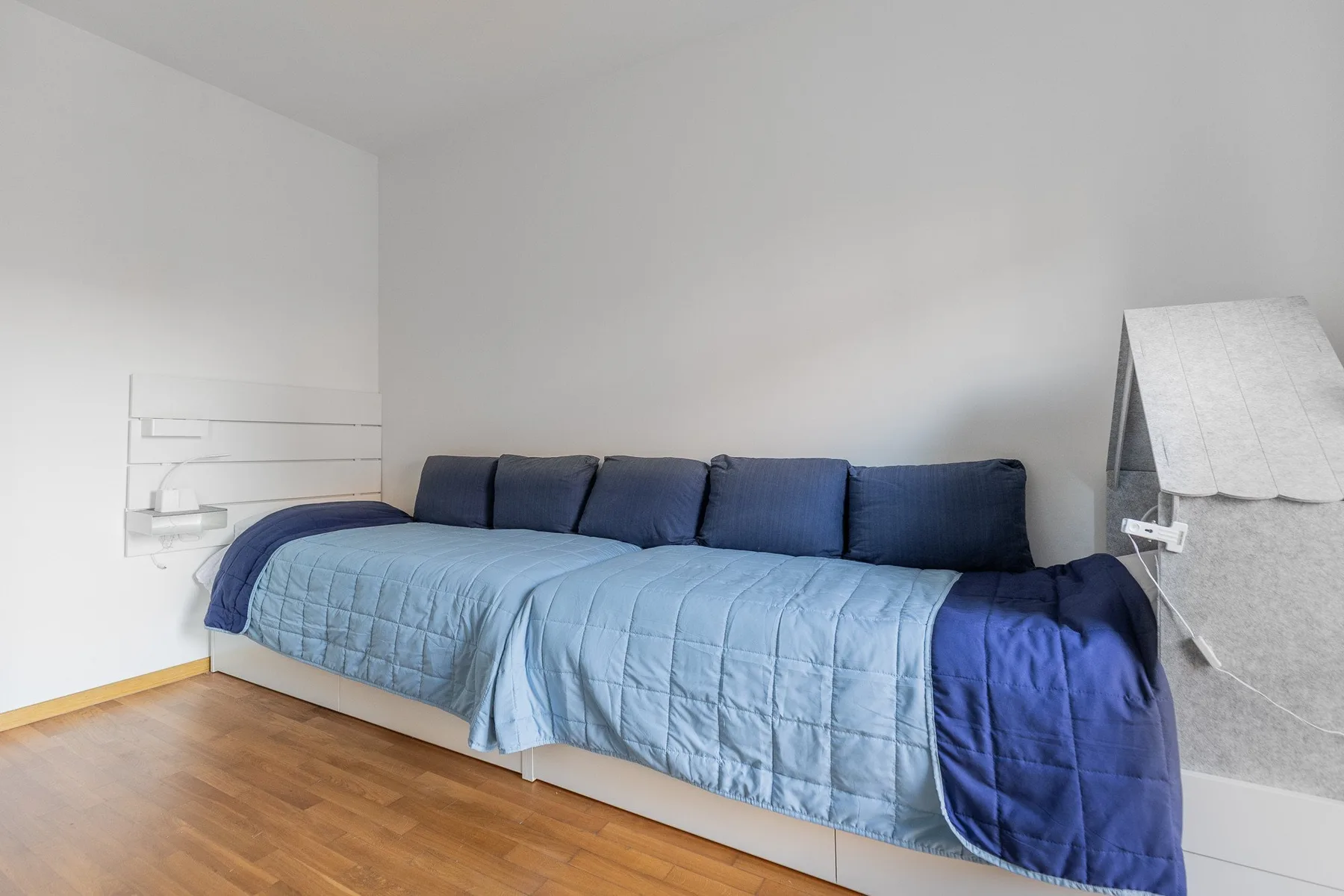 A bedroom with a bed covered in blue bedding and a row of pillows.