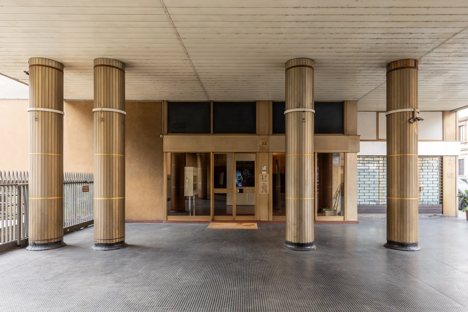 A covered building entrance with glass doors and tall columns.