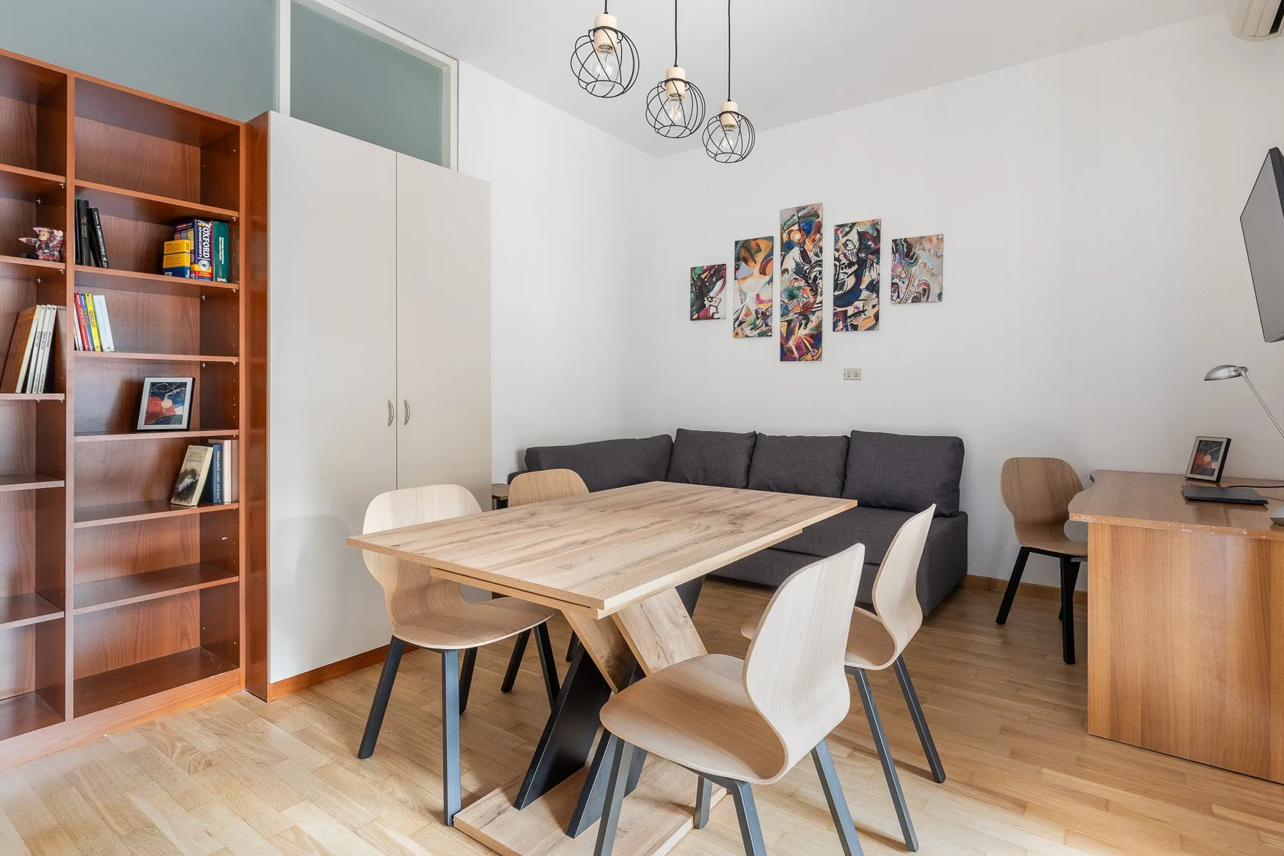 A dining area with a wooden table and chairs in front of a dark sofa.