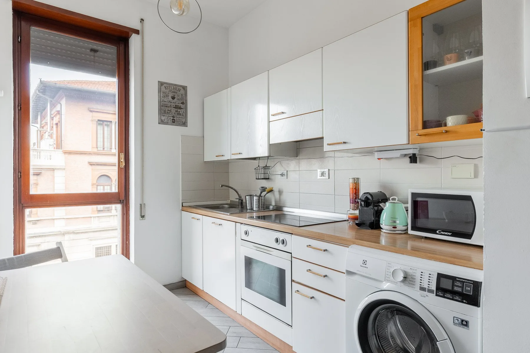 A bright kitchen with white cabinets, a countertop, and a washing machine.