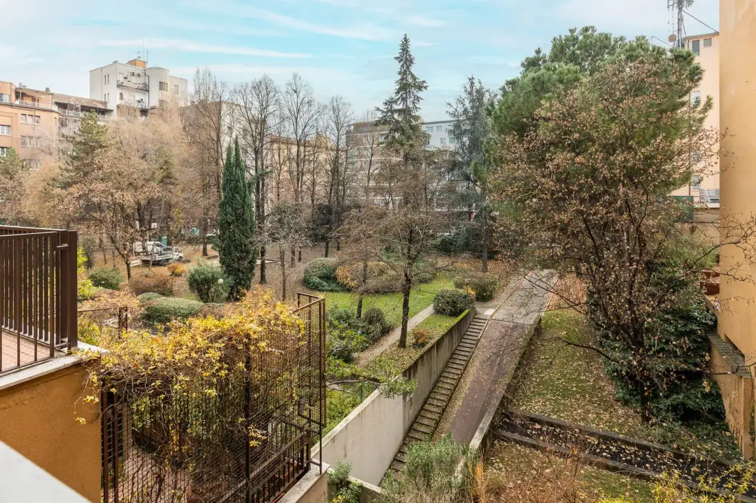 A landscaped courtyard with trees, shrubs, and a paved walkway.