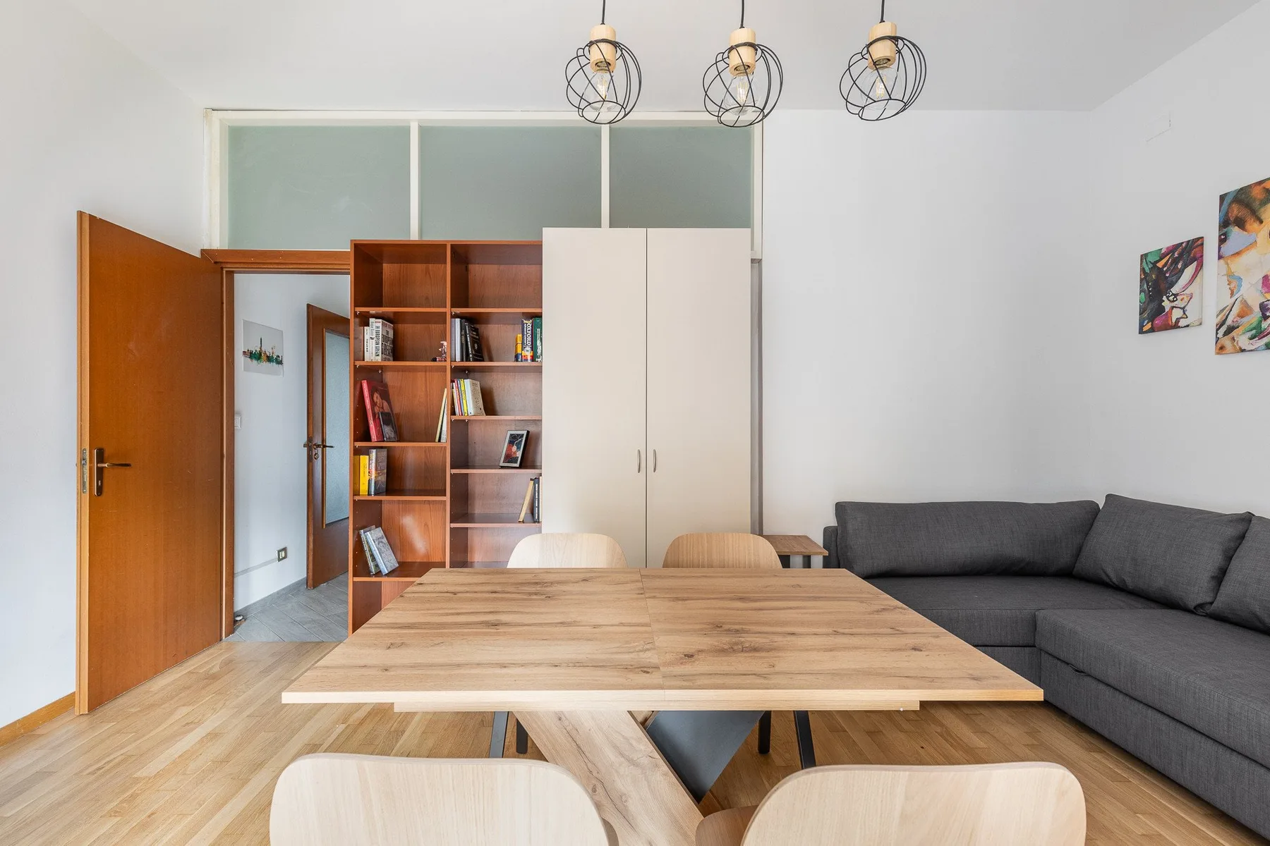 A living room with a wooden dining table and gray seating.
