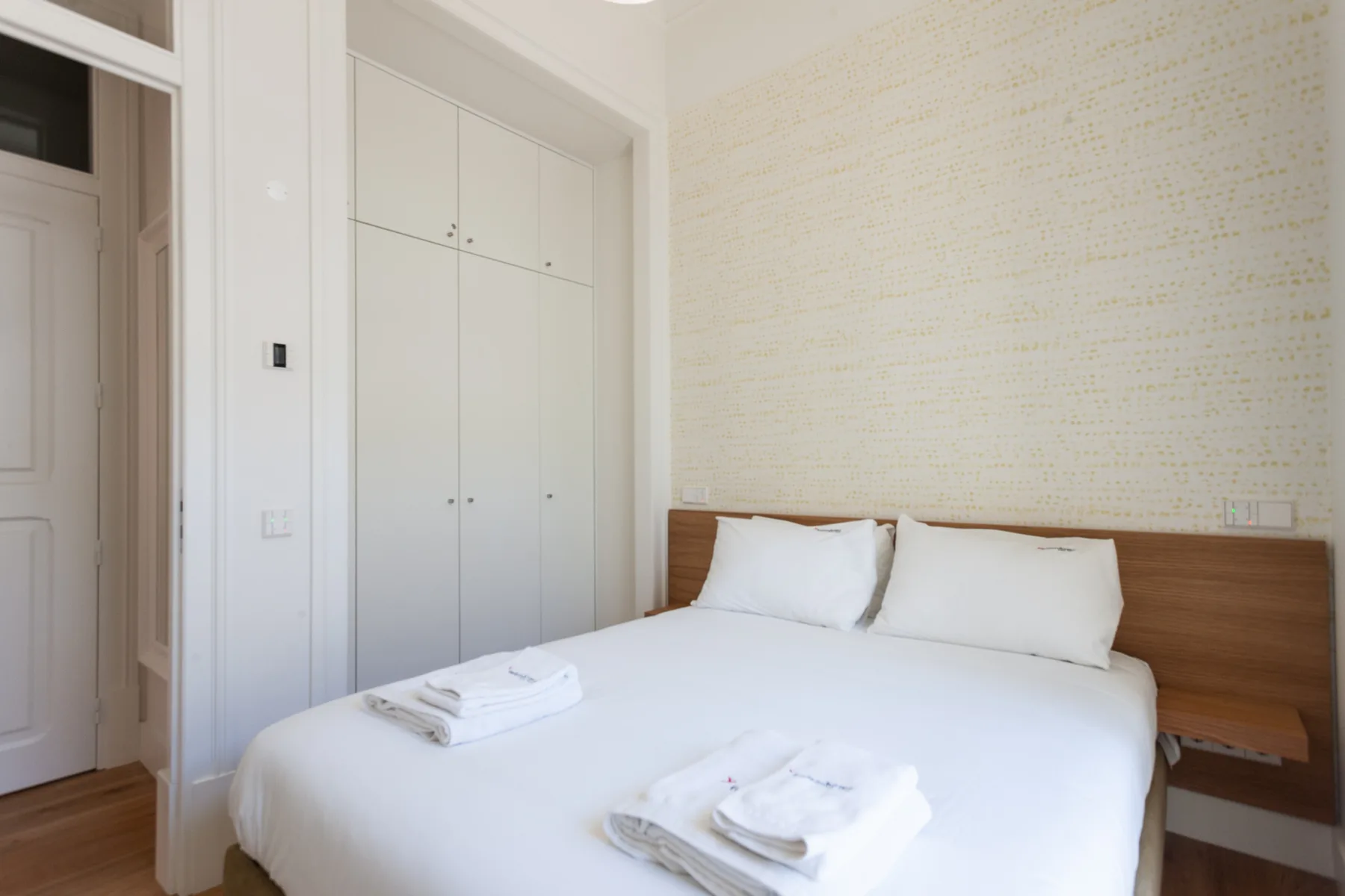 Un dormitorio luminoso con una cama bien hecha y armarios empotrados.