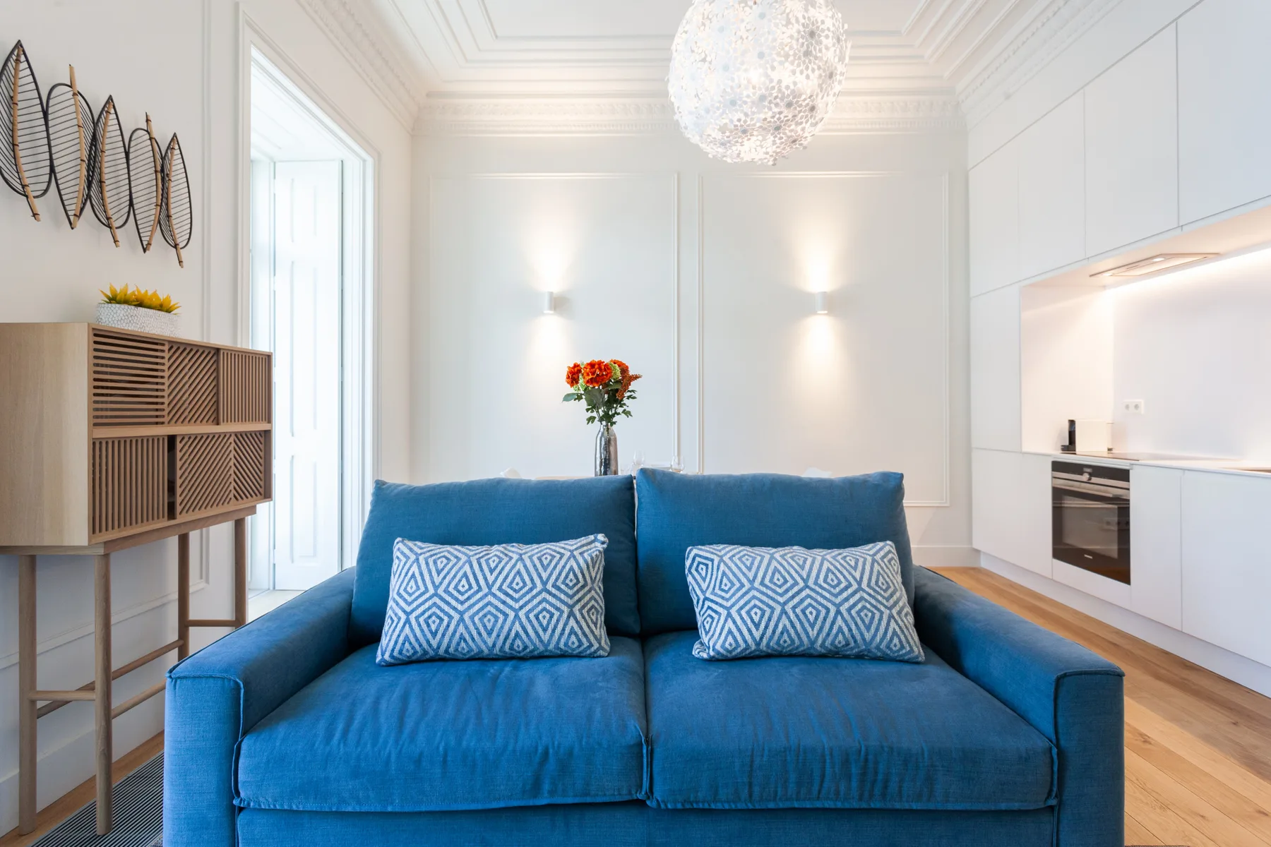 Una sala luminosa con asientos azules y una pequeña zona de cocina.