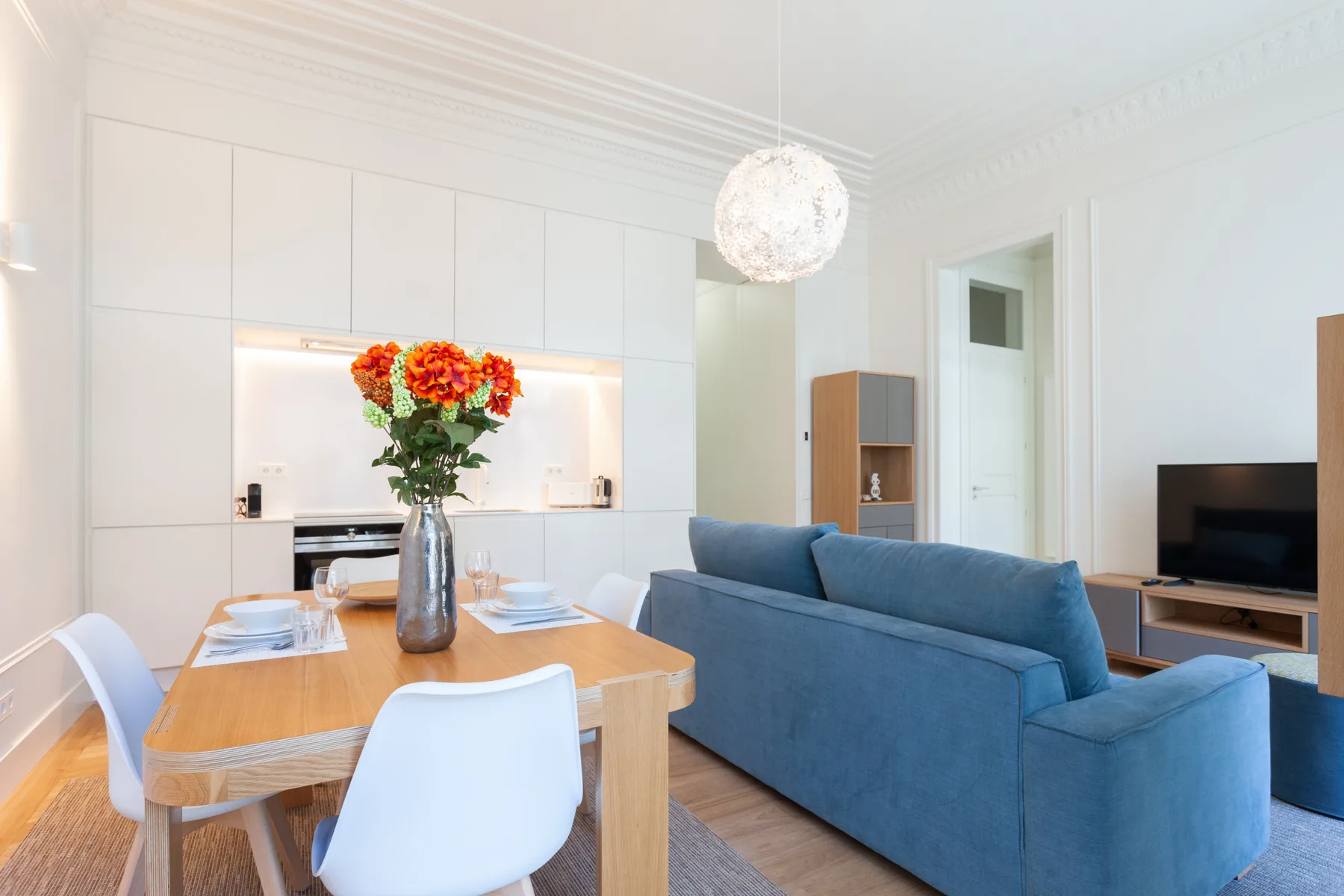 Una luminosa sala de estar y comedor con asientos azules y una mesa de madera.