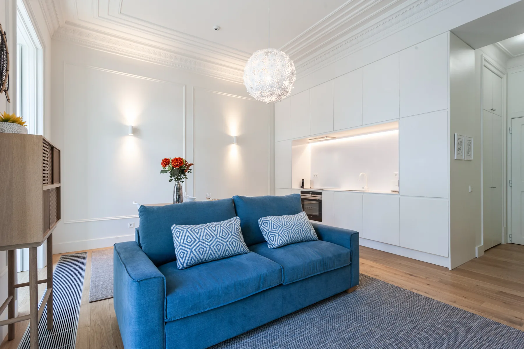 Una sala luminosa con asientos azules y un mueble empotrado.